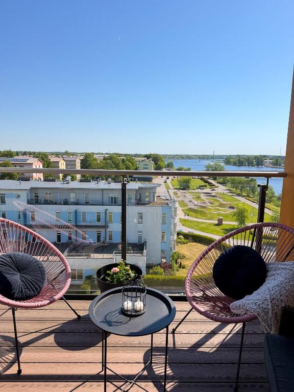 a balcony with three chairs and a table with a view at River Apartment in Pärnu