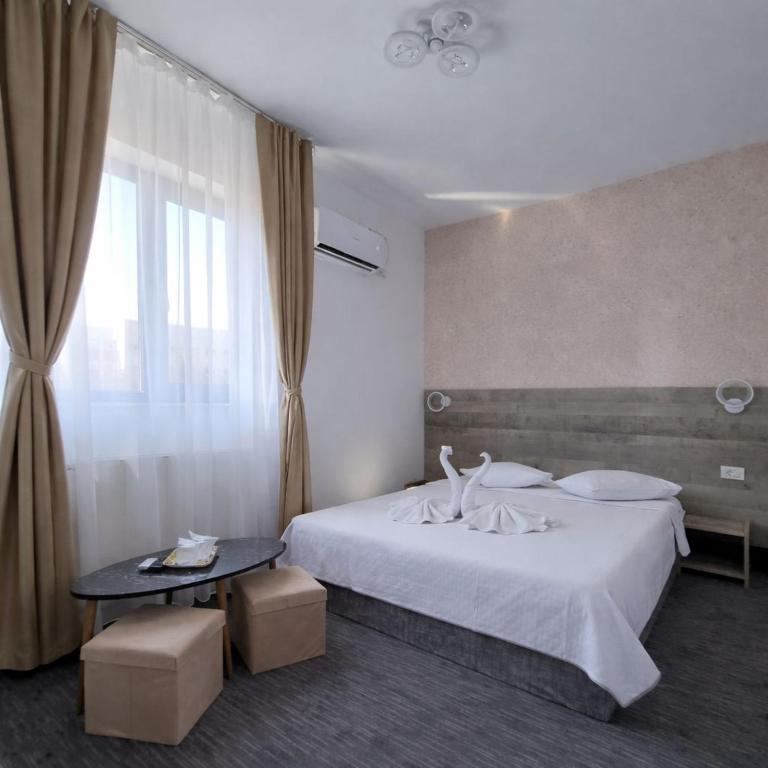 a bedroom with a bed and a table and a window at Hotel Minion in Constanţa