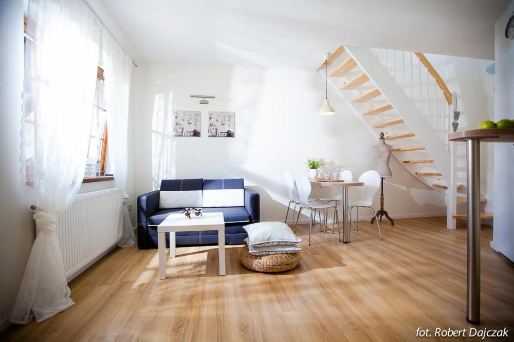 a living room with a blue couch and a staircase at Apartamenty Rogowscy - Apartamenty na wynajem w Rewalu in Rewal