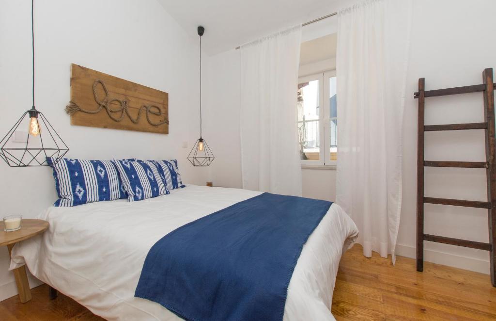 Schlafzimmer mit einem Bett mit blauer und weißer Bettwäsche in der Unterkunft Home Sweet Apartments in Lissabon