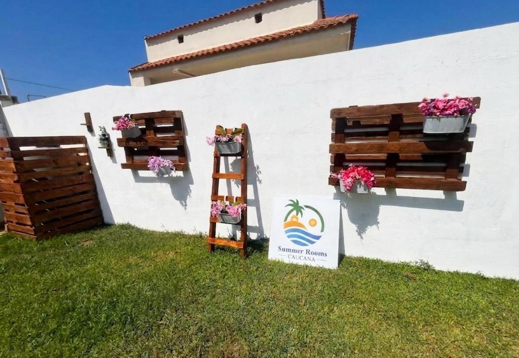 a white wall with two flower boxes and a ladder at Summer Rooms Caucana in Punta Secca