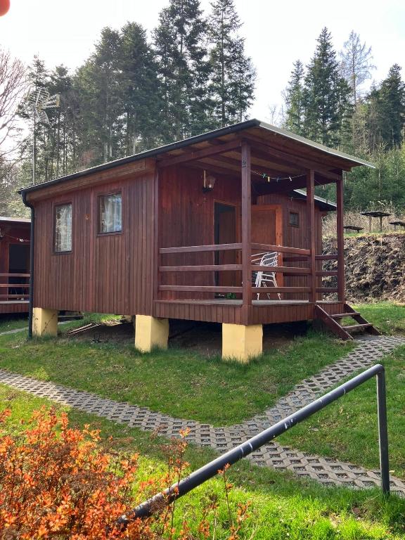 a large wooden cabin with a porch on the grass at Chaty u Toma Slapy in Nalžovice
