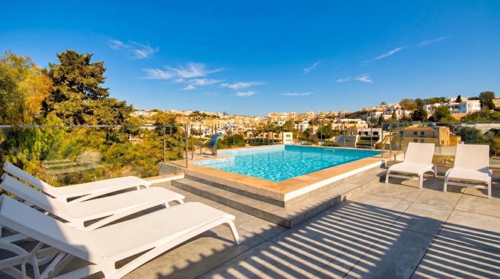 a patio with a pool and two white chairs at Villa Goa - By Luxury Villas Malta in Mellieħa