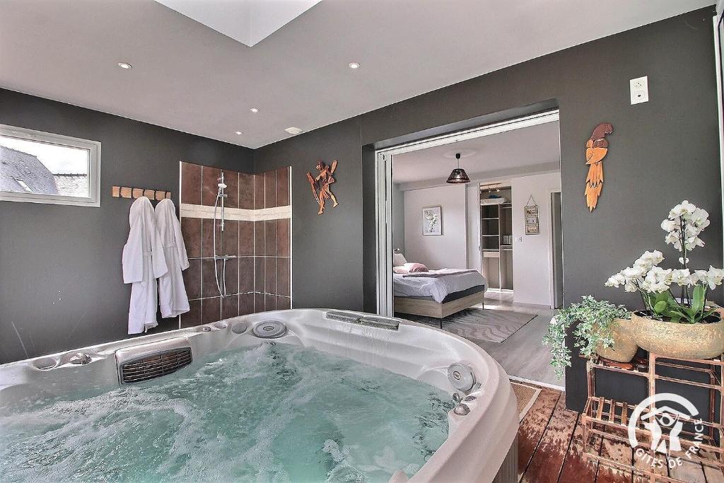 eine große Badewanne in einem Zimmer mit einem Schlafzimmer in der Unterkunft La suite orchidée in Paimpol