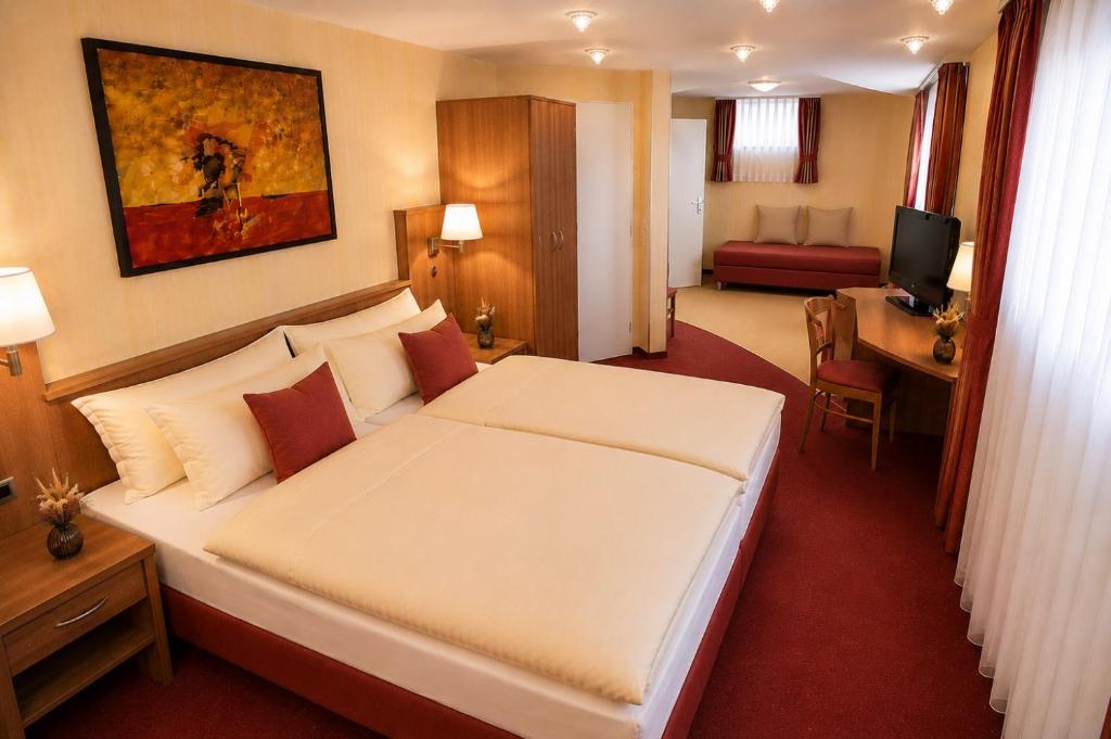 a hotel room with a large bed and a desk at Hotel Altes Rathaus in Ostfildern