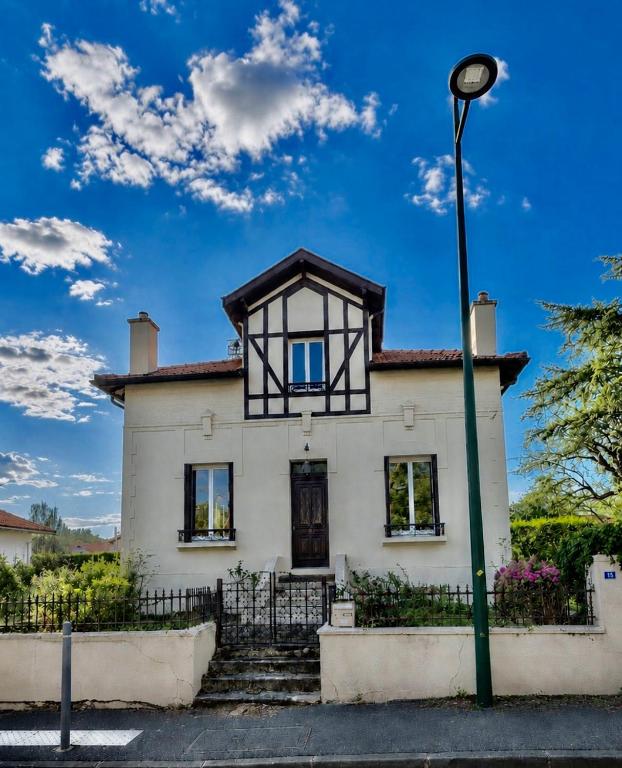 a white house with a black roof and a street light at Maison CÔTE OUEST in Labenne