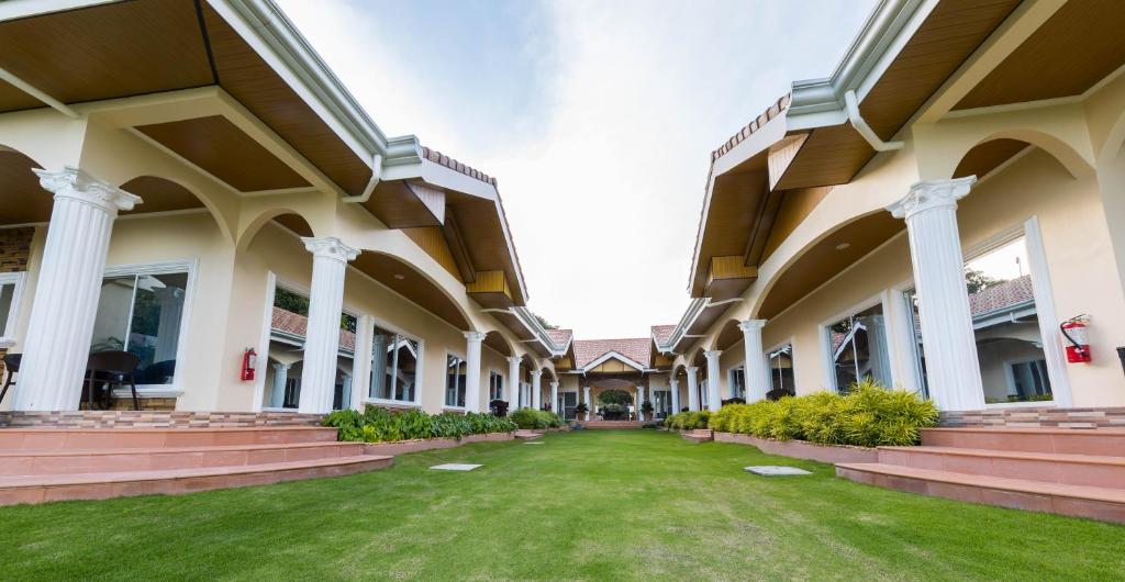 an empty courtyard of a building with columns and grass at 71% Diving Resort in Dumaguete