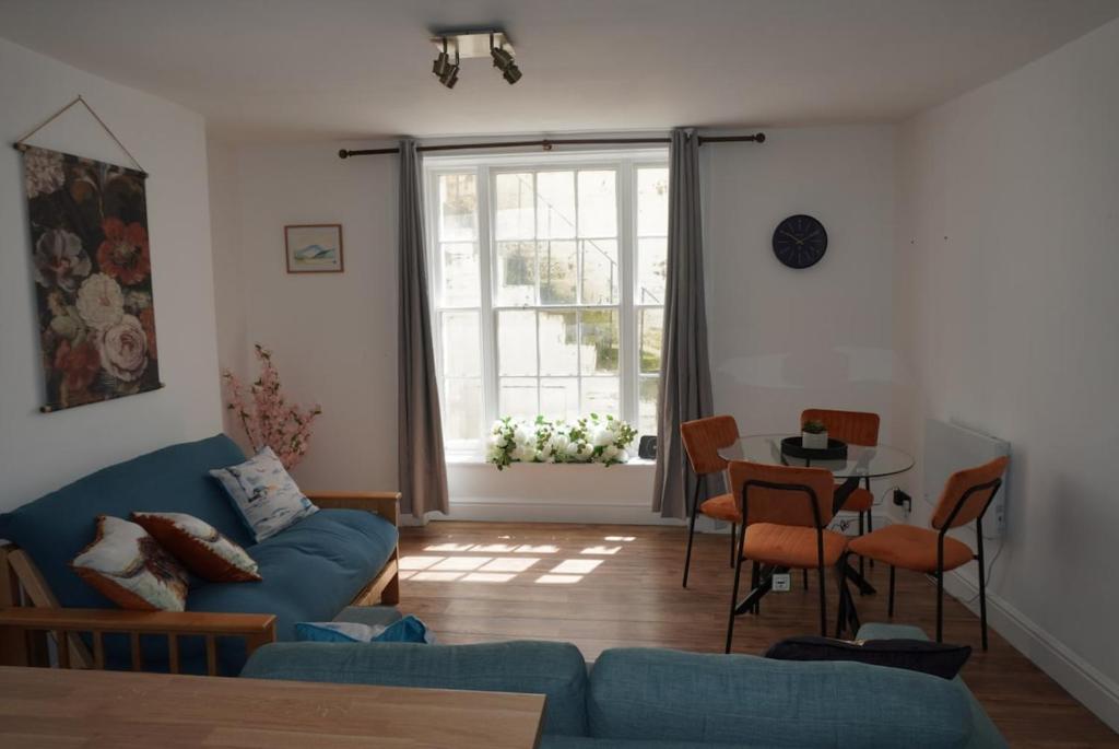 a living room with a blue couch and a table at Garden flat seafront Hastings in Hastings