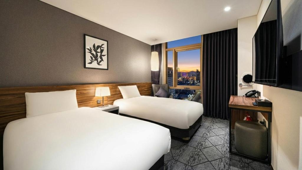 a hotel room with two beds and a window at Staz Hotel Ulsan in Ulsan