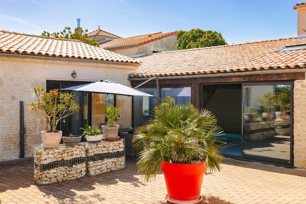 a house with a patio with an umbrella and potted plants at Mimosa in La Jarrie
