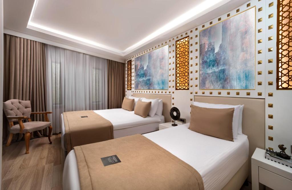 a hotel room with two beds and a chair at Goms Hotel Old City in Istanbul