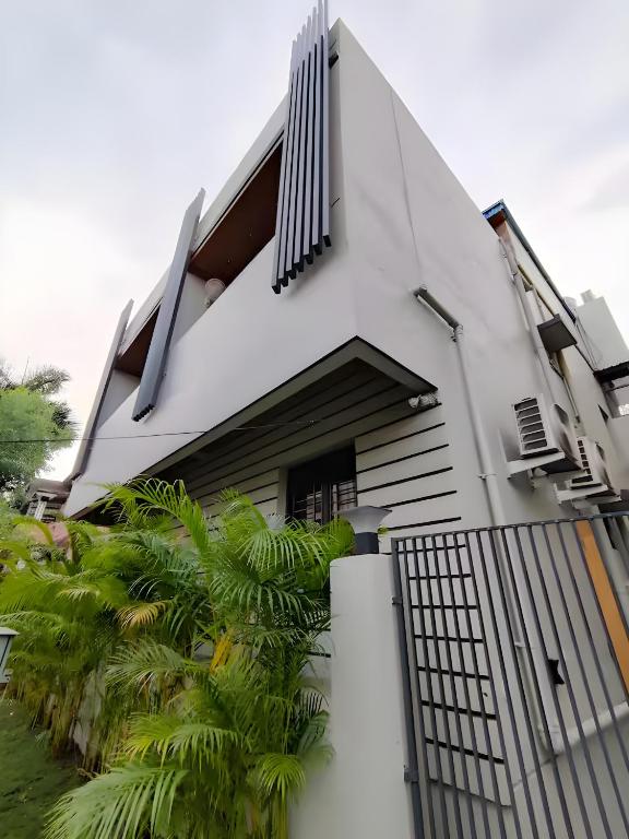 a white house with a gate and palm trees at Stay by Insata Hospitality - Kolkata in Kolkata
