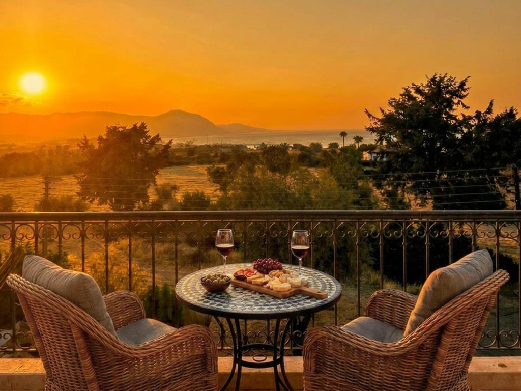 a table with wine glasses and food on a balcony with a sunset at The Summer Haven in Polis Chrysochous