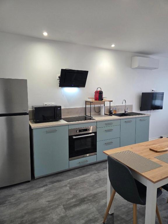 a kitchen with stainless steel appliances and a table at Les Gîtes de Guillonnet in Anglade