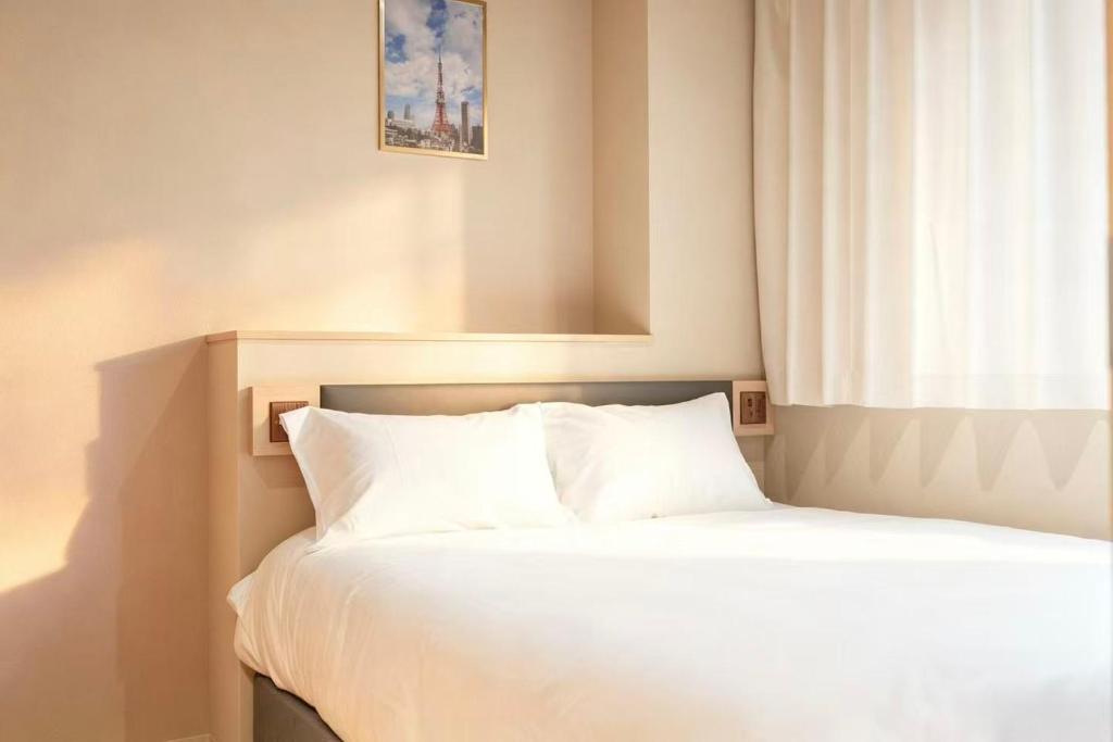 a bedroom with a bed with white sheets and a window at SORA雷門 Hotel in Tokyo