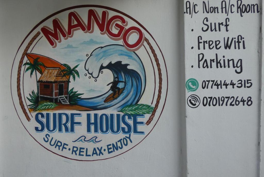 a sign for a surf house on a wall at Mango Surf House in Arugam Bay