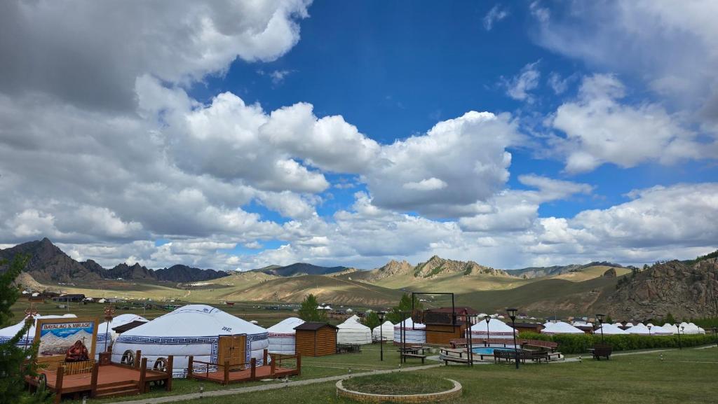 a group of tents in a field with mountains at Bayalag Resort in Yoliin Hural