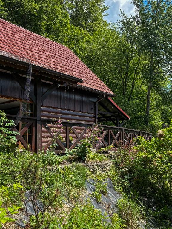 a wooden cabin with a red roof in the woods at Willa Hacienda in Międzybrodzie Żywieckie