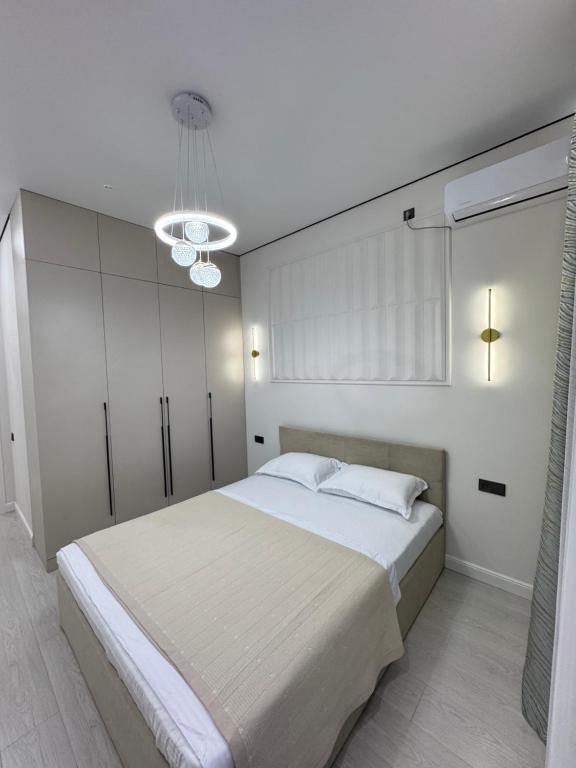 a bedroom with a large white bed and a chandelier at ЖК Ұлы Дала in Shymkent