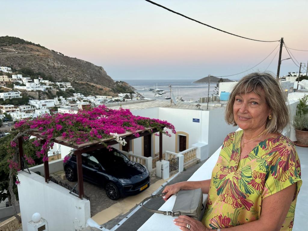 a woman standing on the ledge of a balcony with flowers at Villa Marco Polo in Agia Marina