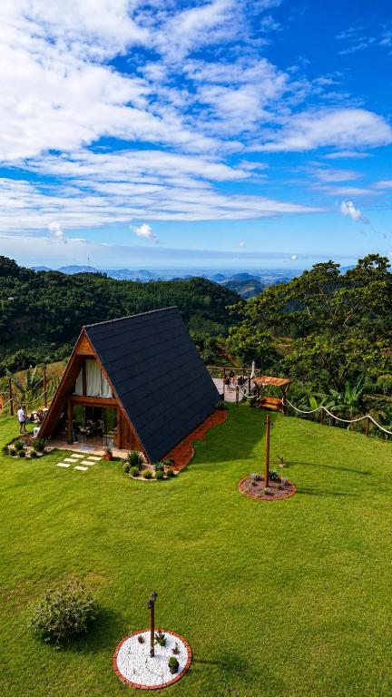 a cabin with a black roof on a green field at Chalés La Montagna in Santa Teresa