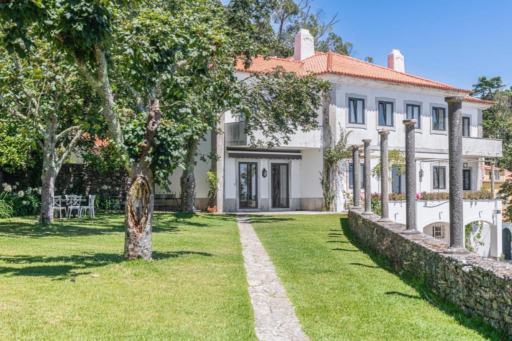 an exterior view of a white house with a yard at Quinta da Paciencia in Sintra