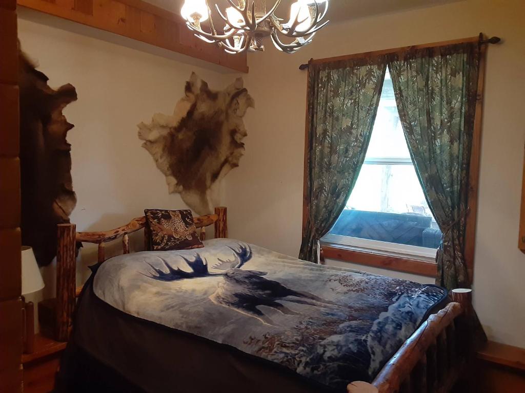 a bedroom with a bed and a chandelier and a window at Hungry Moose B and B in Kasilof