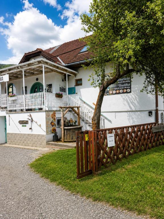 a white house with a fence in front of it at Penzión U Koníka in Liptovský Ján