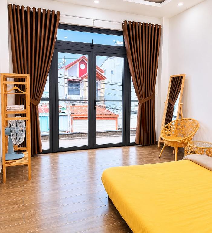 a bedroom with a yellow bed and a large window at La Maison DaLat Home in Ấp Kim Thạch