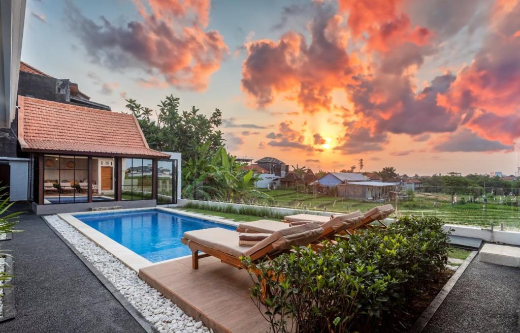 a villa with a swimming pool and a sunset at Emy Kerobokan in Kerobokan