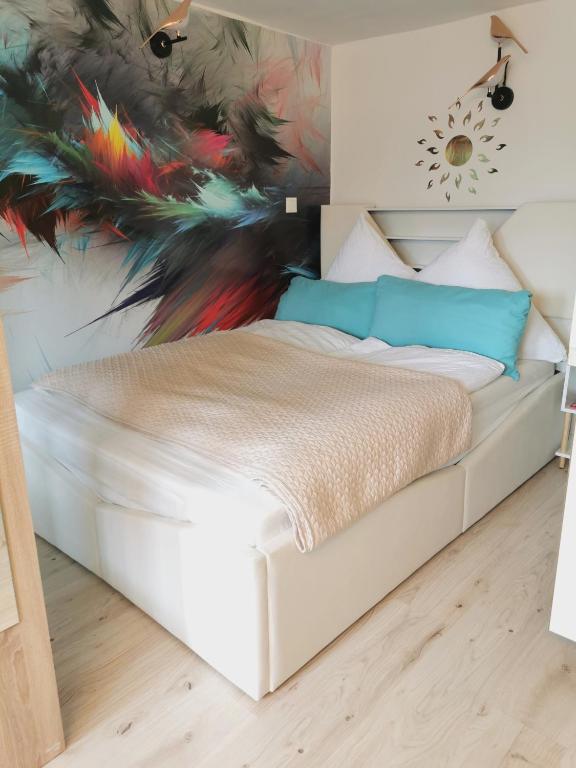 a bedroom with a white bed with a painting on the wall at Ferienwohnung Sonnengarten in Meschede