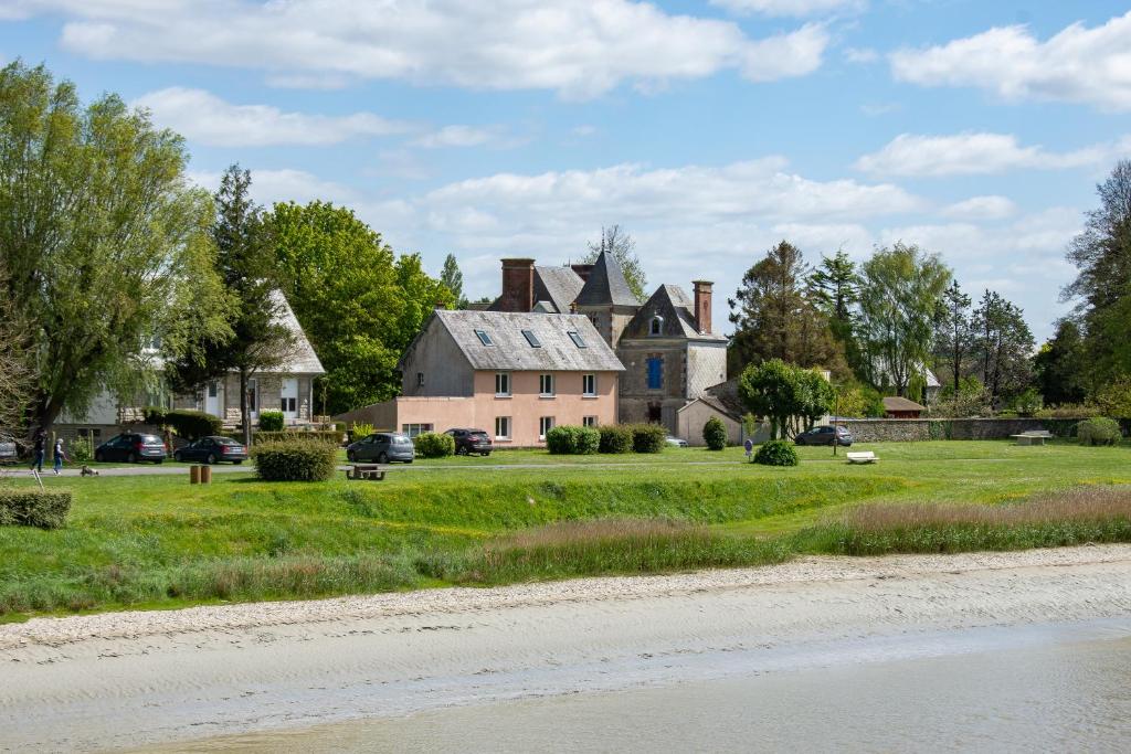 a large house on a grass field next to a road at Hotel Rose in Beauvoir