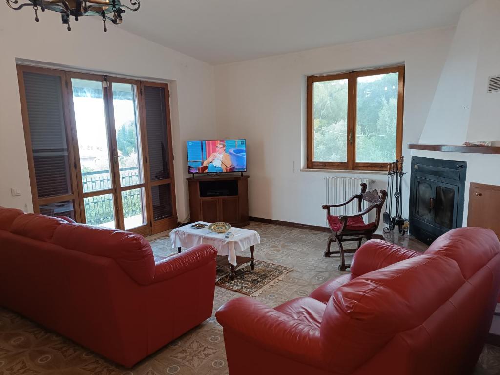 a living room with two red couches and a tv at Casa serusi in Copanello