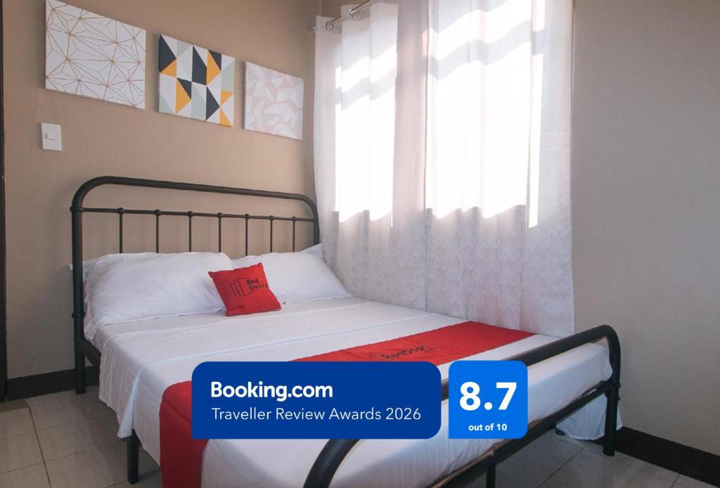a bedroom with a bed and a window at RedDoorz at Aurea Apartelle in Iloilo City