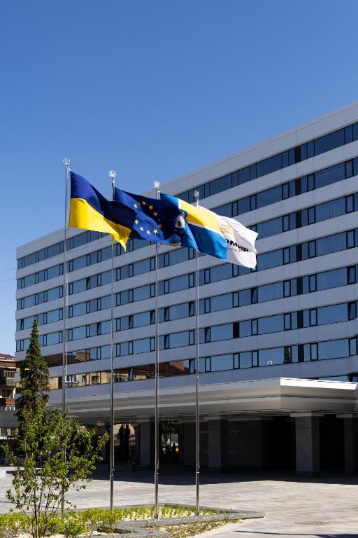 two flags flying in front of a building at Житомир by Optima in Zhytomyr