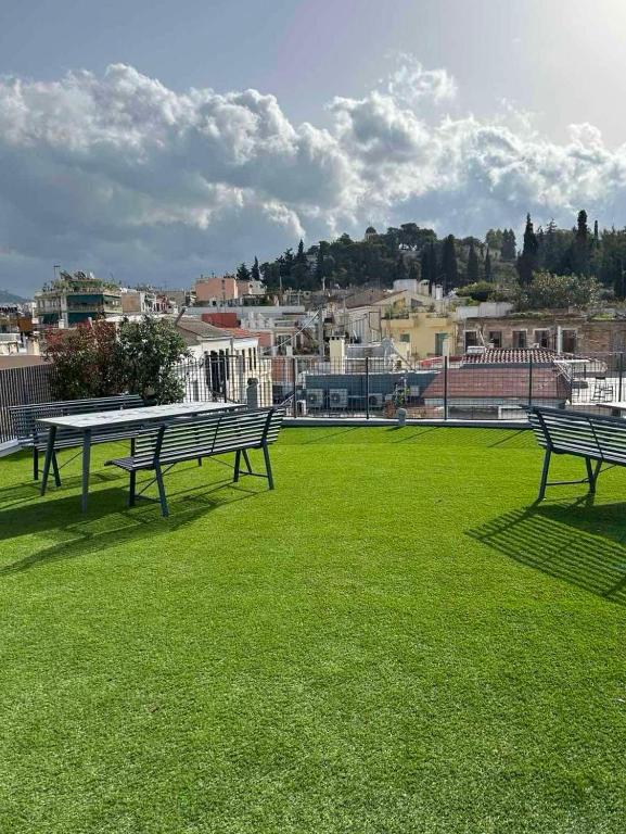 Drei Bänke stehen auf einer Wiese mit Blick auf die Stadt. in der Unterkunft Greece U Around Athens Thissio Suites in Athen