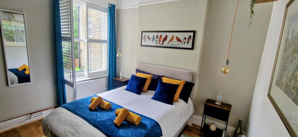 a bedroom with a bed with blue and yellow pillows at Double Bed at Cozy Hailsham in London