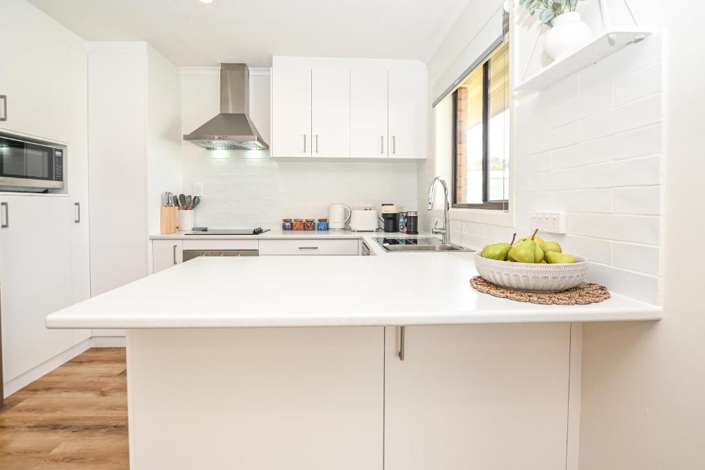 a white kitchen with a bowl of fruit on a counter at Kingscote Getaway Kangaroo Island in Kingscote