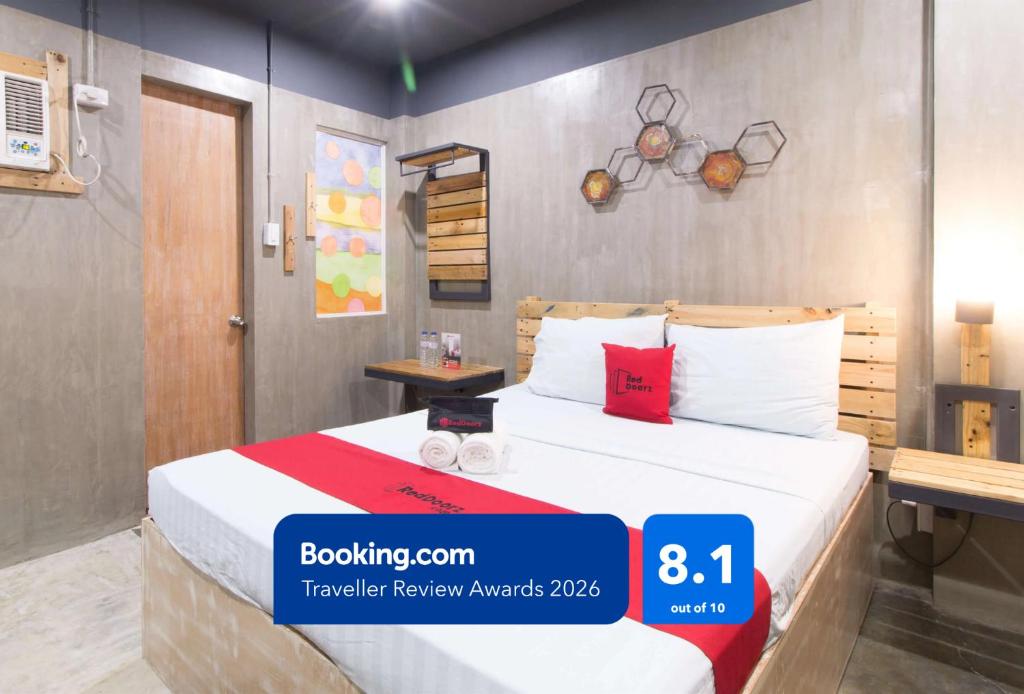 a hotel room with a bed with white sheets and red pillows at RedDoorz Plus @ Taft North Mandurriao in Iloilo City