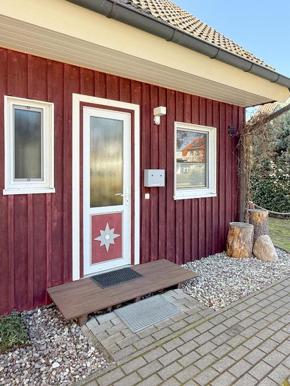 a red house with a red wall with a door at Steuerbord in Prerow