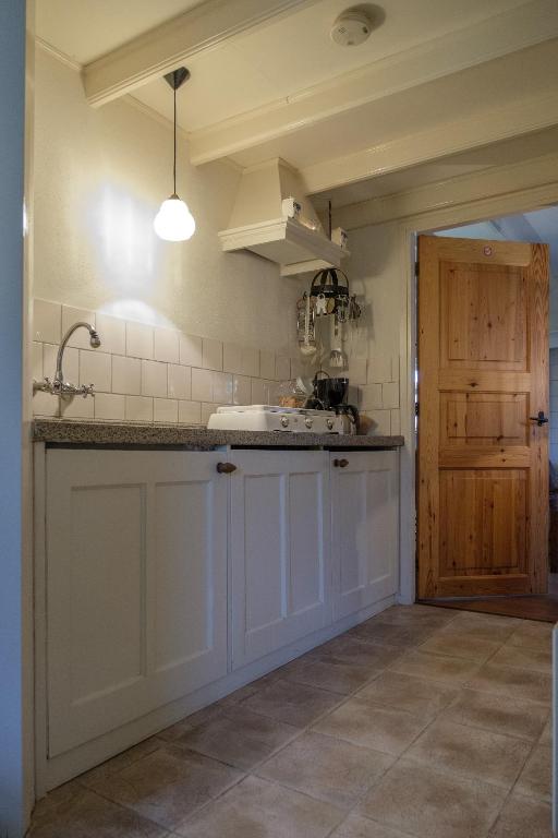 a kitchen with white cabinets and a sink and a door at Oes-Tilber in Zweeloo