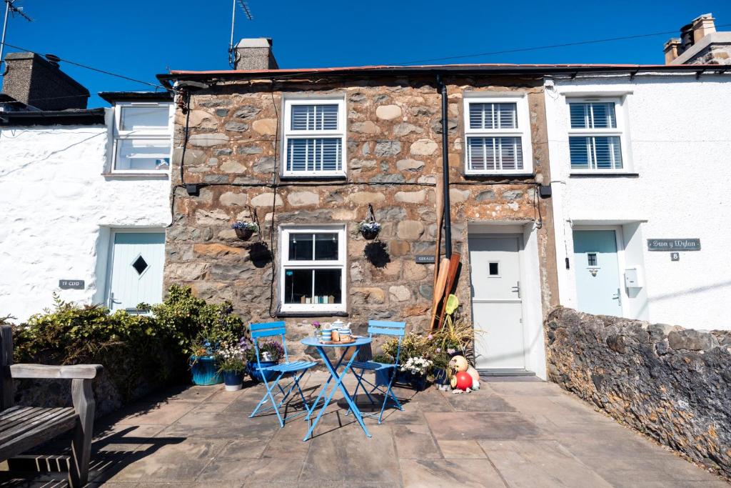 a stone house with a table and chairs in front of it at Gerallt in Pwllheli