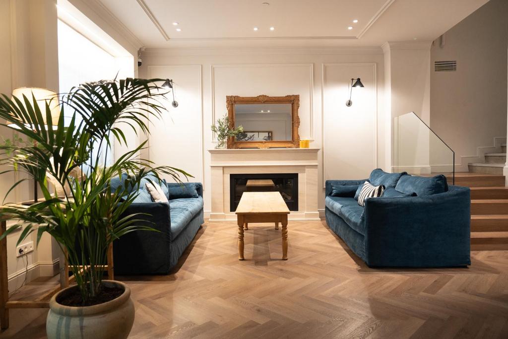a living room with two blue couches and a fireplace at Mesón Castilla Atiram Hotels in Barcelona