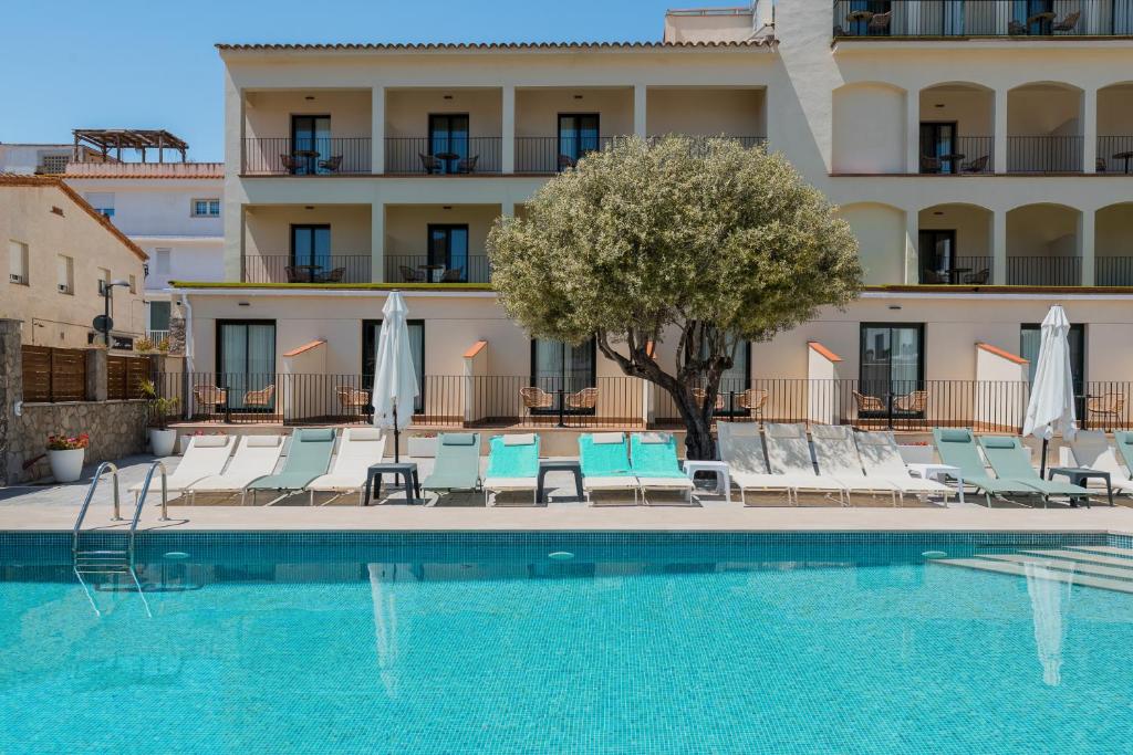 a swimming pool with chairs and a building at Hotel Coral Boutique by gaiarooms in L'Estartit
