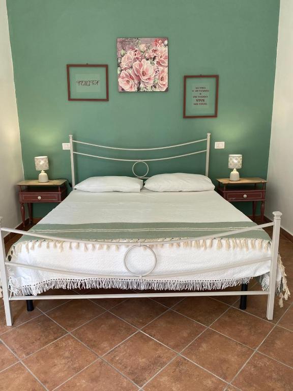 ein Bett in einem Schlafzimmer mit zwei Nachttischen und zwei Bildern in der Unterkunft DaLiù in Itri