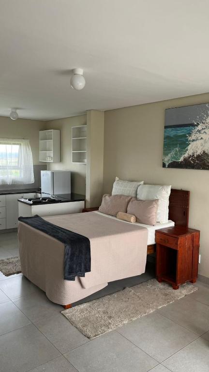 a bedroom with a large bed and a kitchen at Hlalanathi Lodges - Wagendrift Farm in Estcourt