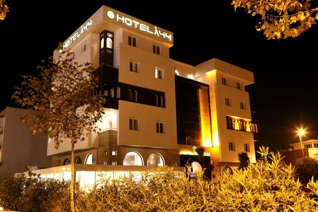 un edificio de hotel con una torre de reloj por la noche en Hotel A44 en Tetuán