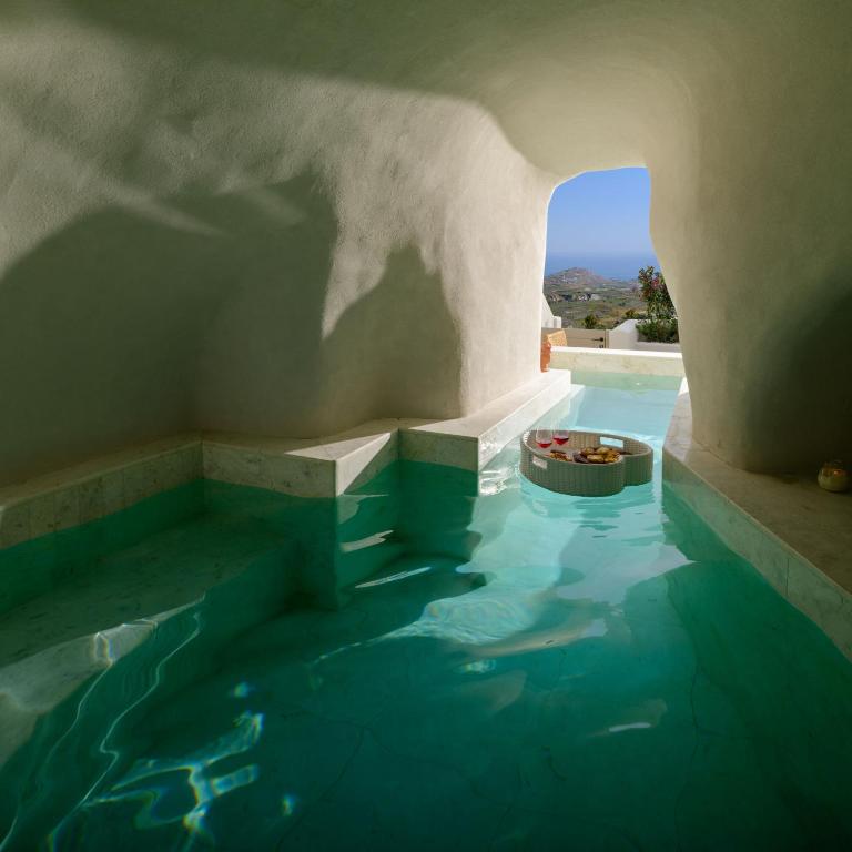 a swimming pool with blue water in a building at Avelora Suites in Pyrgos