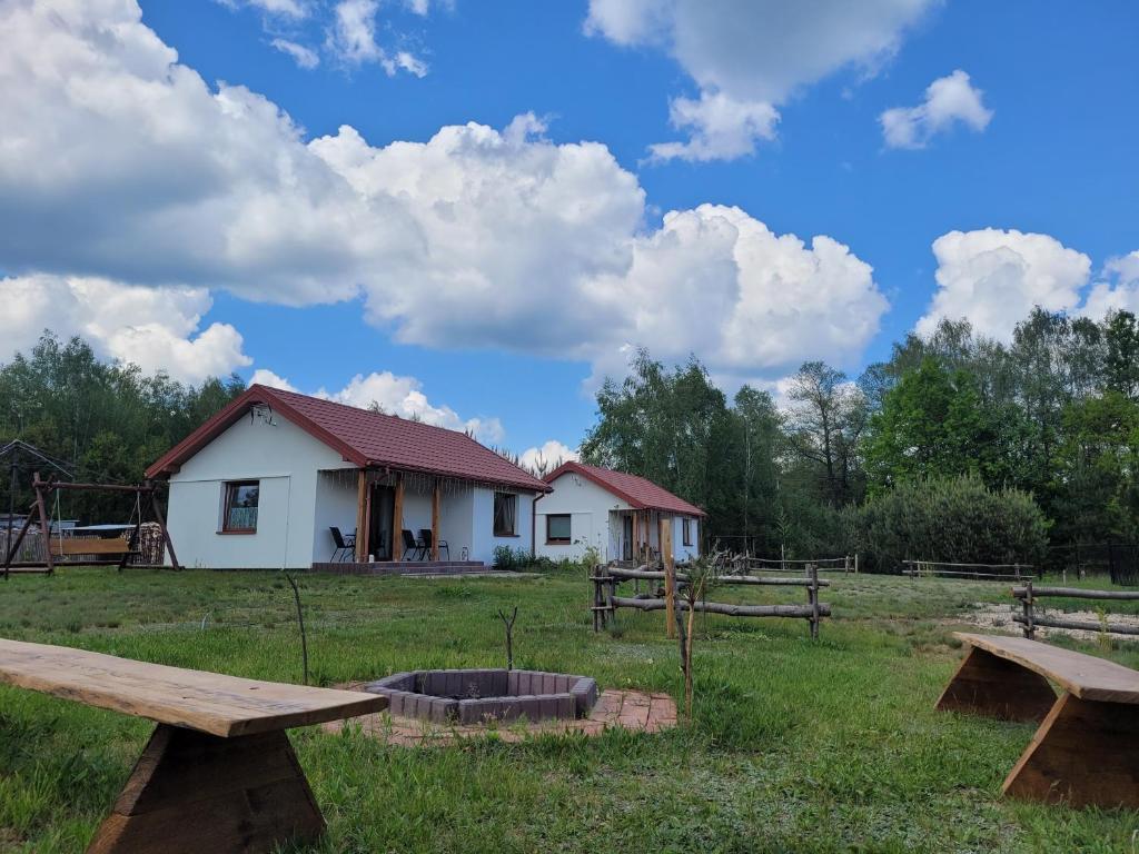 a house in a field with two picnic tables at Domki Strumieniowa in Wólka Tanewska