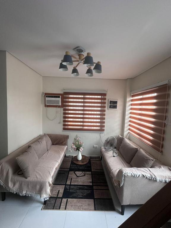 a living room with two couches and two windows at Casa Rufina in Taluc